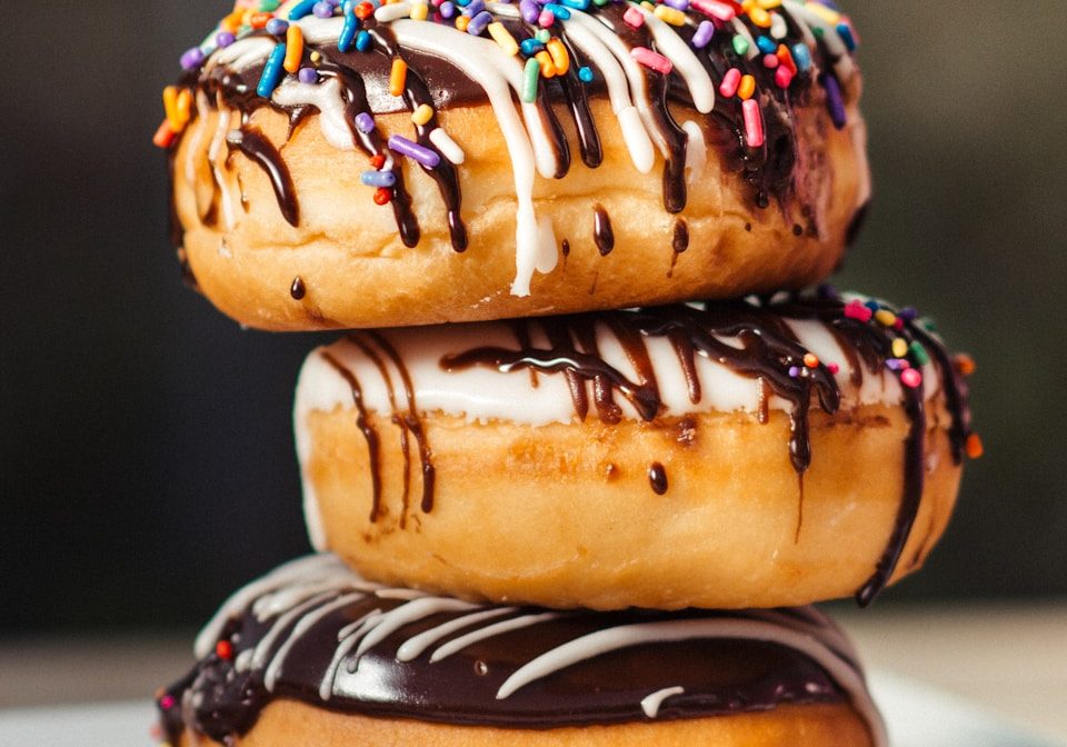 three chocolate-coated donuts with sprinkles